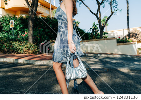 Young caucasian female walking outdoors in stylish summer dress 124831136