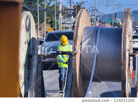 Installation of high-voltage electric wires on new poles along the road 124831203