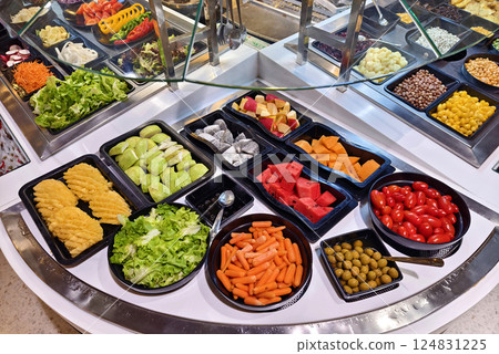 A salad bar featuring an extensive variety of fresh vegetables and fruits A salad bar featuring an extensive variety of fresh vegetables and fruits 124831225