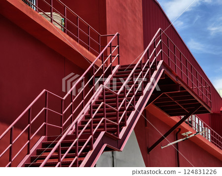 A set of stairs ascending a large red wall A set of stairs ascending a large red wall 124831226
