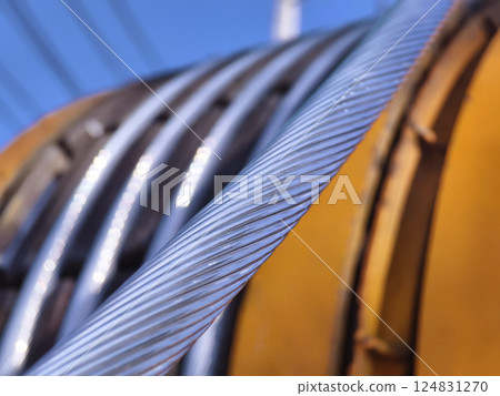 A large wooden spool of high-voltage electric wires is located on the road 124831270