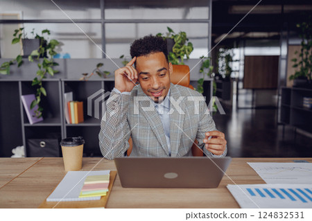 A Professional Individual Engaged in Work at a Laptop within a Contemporary Office Setting 124832531