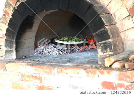 Pizza baking in a wood-fired pizza oven - food background material Pizza baking in a wood-fired pizza oven - food background material 124832629