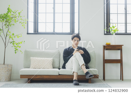 一個在客廳裡使用智能手機的人 一個在客廳裡使用智能手機的人 124832900