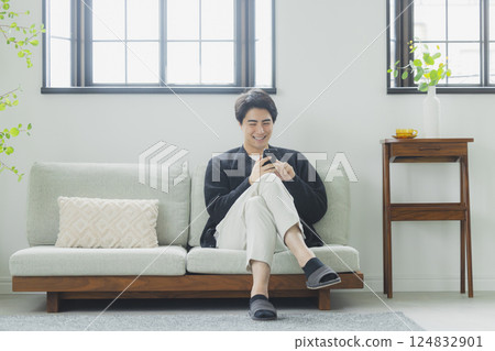 一個在客廳裡使用智能手機的人 124832901