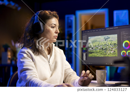 Video editor analyzing film montage before editing color balance and lighting in creative office. Post production studio employee working with raw footage while listening music in headphones Video editor analyzing film montage before editing color balance and lighting in creative office. Post production studio employee working with raw footage while listening music in headphones 124833127
