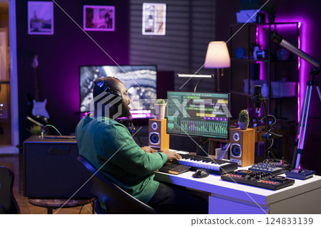 Audio producer playing piano electronic synthesizer to create a new tune, adjusting volume levels on old recordings. Music engineer recording sounds, plays tracks on midi controller. Audio producer playing piano electronic synthesizer to create a new tune, adjusting volume levels on old recordings. Music engineer recording sounds, plays tracks on midi controller. 124833139