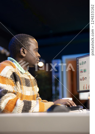 Entrepreneur doing remote work using monthly revenue balance, examining statistics at his workstation. Investment advisor planning new strategy to obtain more funds for global development. Entrepreneur doing remote work using monthly revenue balance, examining statistics at his workstation. Investment advisor planning new strategy to obtain more funds for global development. 124833162