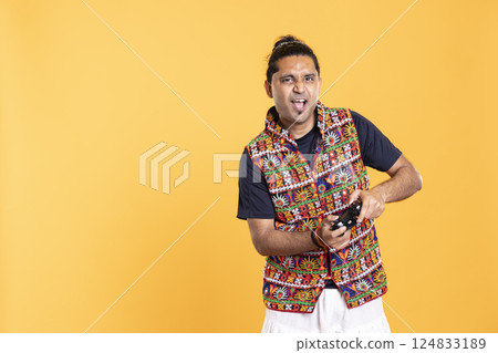 Cheerful man playing videogames with controller, studio background. Portrait of gamer smiling, having fun by participating in PvP online multiplayer game using console system Cheerful man playing videogames with controller, studio background. Portrait of gamer smiling, having fun by participating in PvP online multiplayer game using console system 124833189