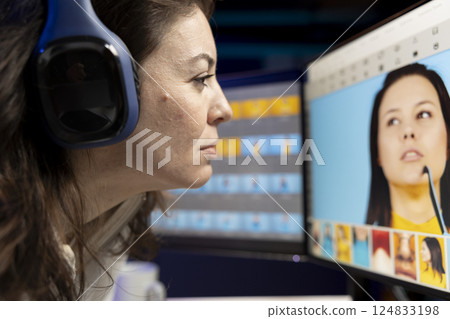 Content specialist selecting best editorial pictures for social media while listening music through headphones. Expert editing photos in advertising agency office, close up 124833198