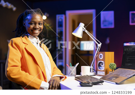 Portrait of smiling software developer writing code on laptop screen in apartment office using Java programming languages. Happy gen Z programmer remotely working from home, fixing database errors 124833199