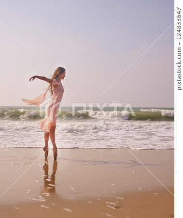 Graceful ballerina on pointe by the sea wearing a flowing pink dress at sunset Graceful ballerina on pointe by the sea wearing a flowing pink dress at sunset 124833647