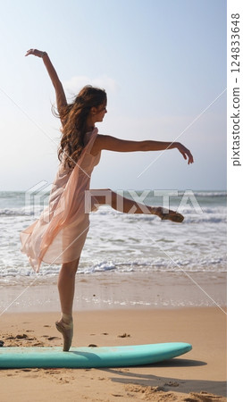 Unusual contrast of ballerina standing on surfboard in elegant beach performance 124833648