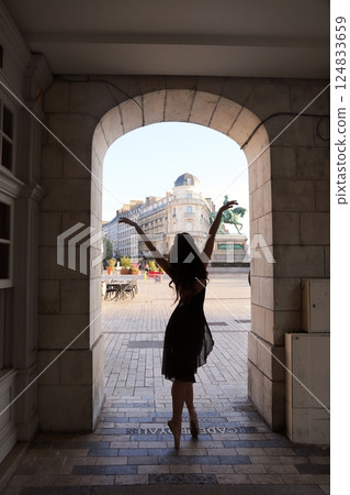 Ballerina dancing under arch in city square 124833659
