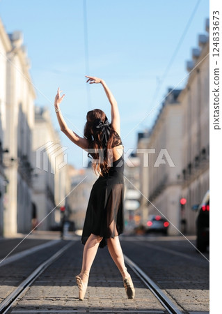 Ballerina posing en pointe on city tram tracks 124833673