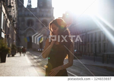 Woman in black dress walking in sun flare 124833697