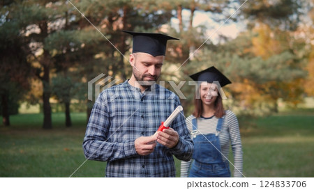 Two proud graduates celebrate their achievements outdoors, showcasing joy and accomplishment with enthusiasm 124833706