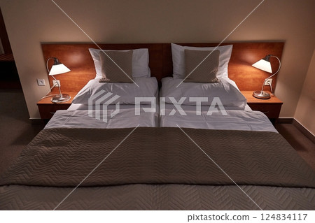 Hotel bed with white sheets, cozy lighting Hotel bed with white sheets, cozy lighting 124834117