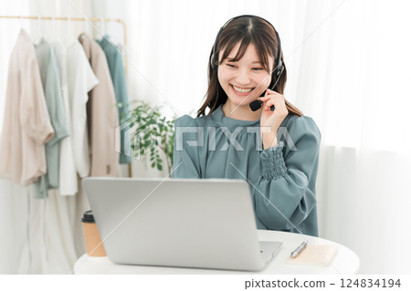 A woman wearing a headset and using a computer 124834194