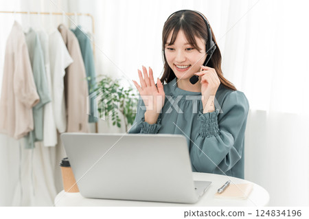 A woman wearing a headset and using a computer A woman wearing a headset and using a computer 124834196