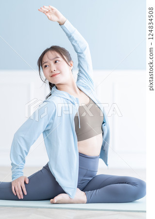 一位身穿長袖的年輕女子在明亮的房間裡伸展身體 一位身穿長袖的年輕女子在明亮的房間裡伸展身體 124834508
