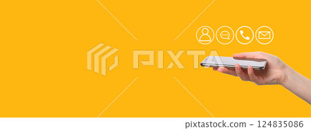A hand presents a modern smartphone in front of a vibrant yellow backdrop with icons A hand presents a modern smartphone in front of a vibrant yellow backdrop with icons 124835086