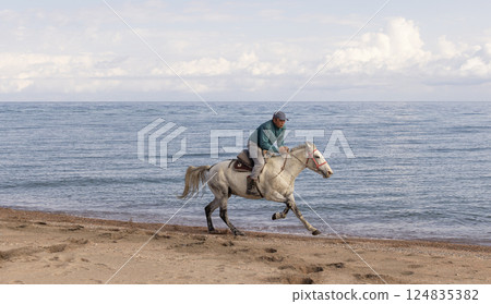 rider run with his horse on the  Issyk-Kul lakeside.  Kyrgyzstani is nomads in central asia 124835382