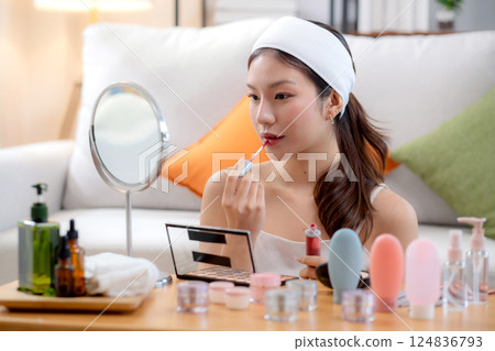 Beauty happy young asian woman applying makeup with lipstick looking mirror in living room. 124836793