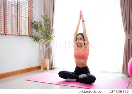 Young asian woman meditation sitting on mat in serene and tranquility with yoga in living room. Young asian woman meditation sitting on mat in serene and tranquility with yoga in living room. 124836822