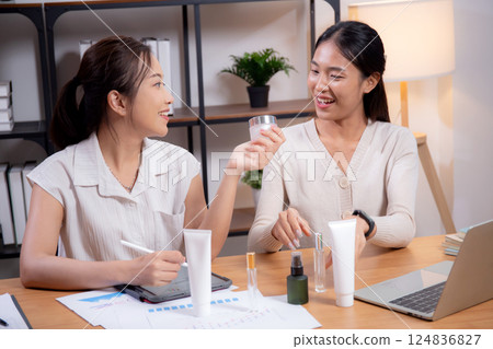 Two asian businesswoman testing and researching cosmetic product or cream in bottle in office. 124836827