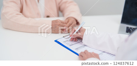 senior woman consulting with doctor in hospital. Elderly patient talking and sharing disease. Doctor listens, asking question and taking note. medical consultation and geriatric Healthcare concept 124837612