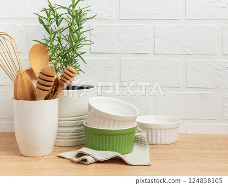 Kitchen utensils, rosemary plant, and ramekins creating a cozy culinary scene 124838105