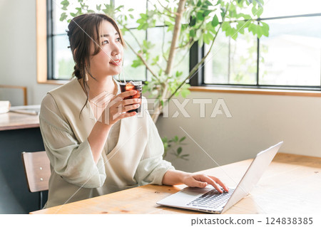 A woman working remotely while drinking iced coffee in a cafe A woman working remotely while drinking iced coffee in a cafe 124838385