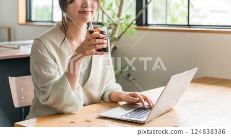A woman working remotely while drinking iced coffee in a cafe A woman working remotely while drinking iced coffee in a cafe 124838386
