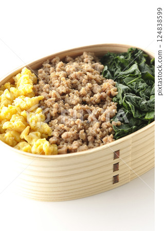 Three-color bento box with egg, meat, and spinach photographed on white background 124838599
