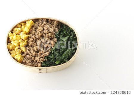 Three-color bento box with egg, meat, and spinach photographed on white background 124838613
