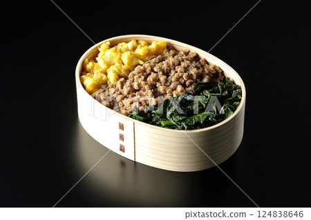 Three-color bento box with egg, meat, and spinach photographed against a black background Three-color bento box with egg, meat, and spinach photographed against a black background 124838646