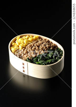 Three-color bento box with egg, meat, and spinach photographed against a black background Three-color bento box with egg, meat, and spinach photographed against a black background 124838655