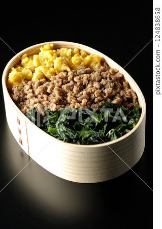 Three-color bento box with egg, meat, and spinach photographed against a black background Three-color bento box with egg, meat, and spinach photographed against a black background 124838658