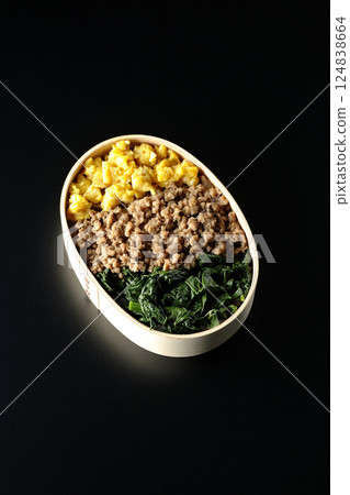 Three-color bento box with egg, meat, and spinach photographed against a black background Three-color bento box with egg, meat, and spinach photographed against a black background 124838664