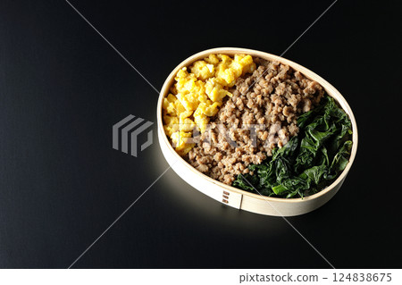 黑色背景下拍攝的三色便當盒,內有雞蛋、肉和菠菜 黑色背景下拍攝的三色便當盒,內有雞蛋、肉和菠菜 124838675