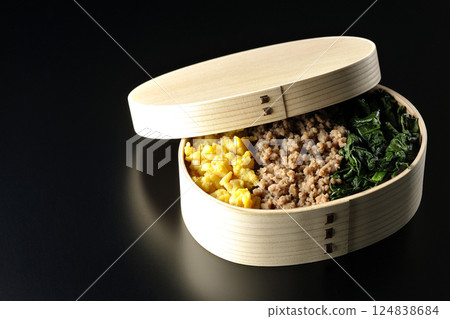 Three-color bento box with egg, meat, and spinach photographed against a black background Three-color bento box with egg, meat, and spinach photographed against a black background 124838684