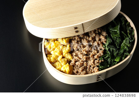 黑色背景下拍攝的三色便當盒,內有雞蛋、肉和菠菜 黑色背景下拍攝的三色便當盒,內有雞蛋、肉和菠菜 124838698