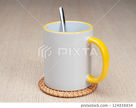 Two-tone 11oz mug on the mug coaster on the table. Mug with tea spoon. Mug with yellow handle and inner part. Two-tone 11oz mug on the mug coaster on the table. Mug with tea spoon. Mug with yellow handle and inner part. 124838834