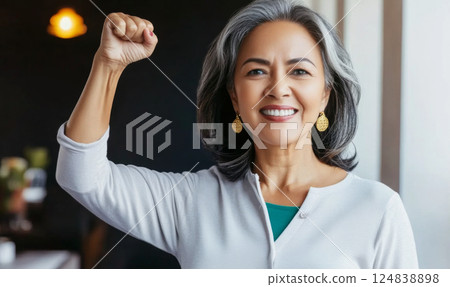 Middle aged hispanic woman with raised fist of empowerment, strength and women solidarity, International Womens Day concept 124838898