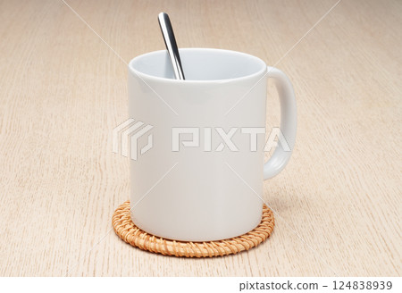Blank 11oz white mug on the coaster on the table. Mug with spoon. Blank 11oz white mug on the coaster on the table. Mug with spoon. 124838939