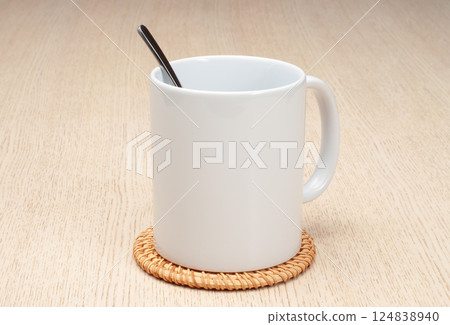 Blank 11oz white mug on the coaster on the table. Mug with spoon. Blank 11oz white mug on the coaster on the table. Mug with spoon. 124838940
