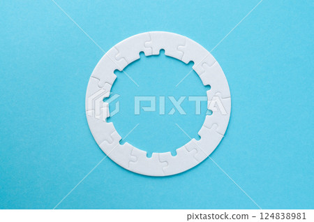White circle jigsaw puzzle as a frame on the blue background. Top view of jigsaw puzzle. 124838981