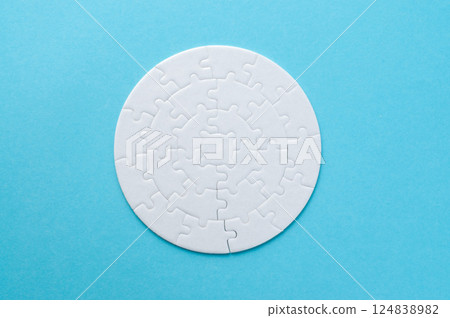 White circle jigsaw puzzle on the blue background. Top view of jigsaw puzzle. 124838982