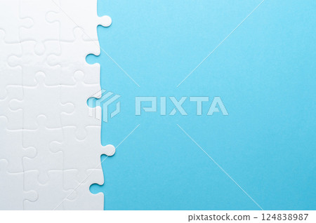Concept for problem-solving, teamwork, solutions, or missing connections. White jigsaw puzzle on a vibrant blue background with one missing piece. Minimalist composition with copy space. Concept for problem-solving, teamwork, solutions, or missing connections. White jigsaw puzzle on a vibrant blue background with one missing piece. Minimalist composition with copy space. 124838987